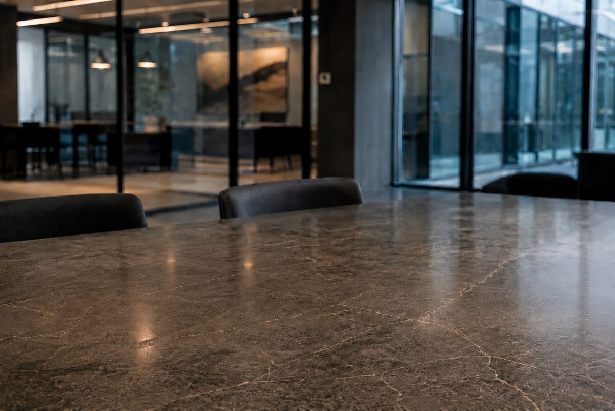 A polished stone table in a quiet office lounge with glass partitions.
